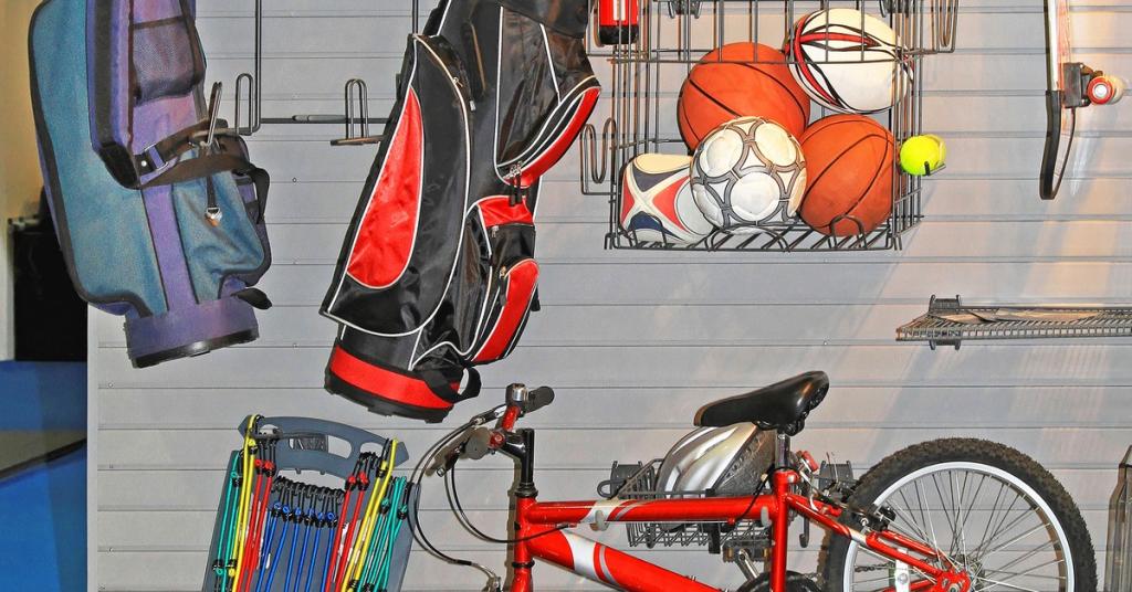 Several items, which include a bike, a golf set, and sports balls, are all attached to a garage wall.