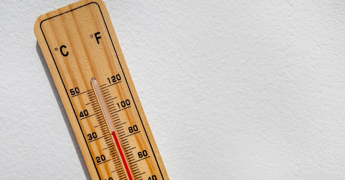 A thermometer is on a white surface. The mercury in the glass tube indicates the temperature is 30 degrees Celsius.