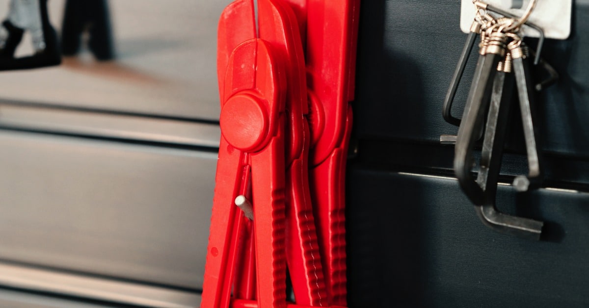 Several items are resting on a wall-mounted hanging system. One of the items is a wire clipper.