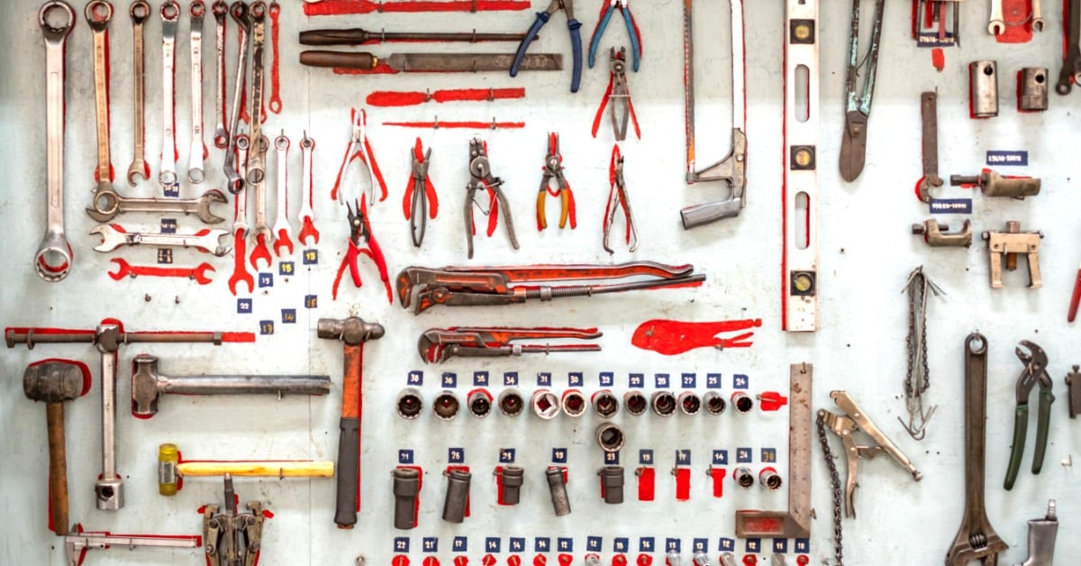 A wall is filled with various different tools. Some of the tools ae clippers while others are hammers.