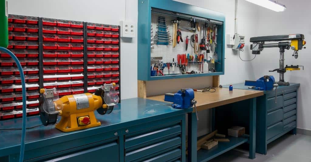 A workshop with tools and tables pushed up against the wall. The walls are white and without decoration.