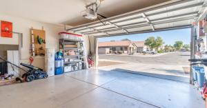 A garage with the door open. There are residential homes across the street with a truck in the driveway.