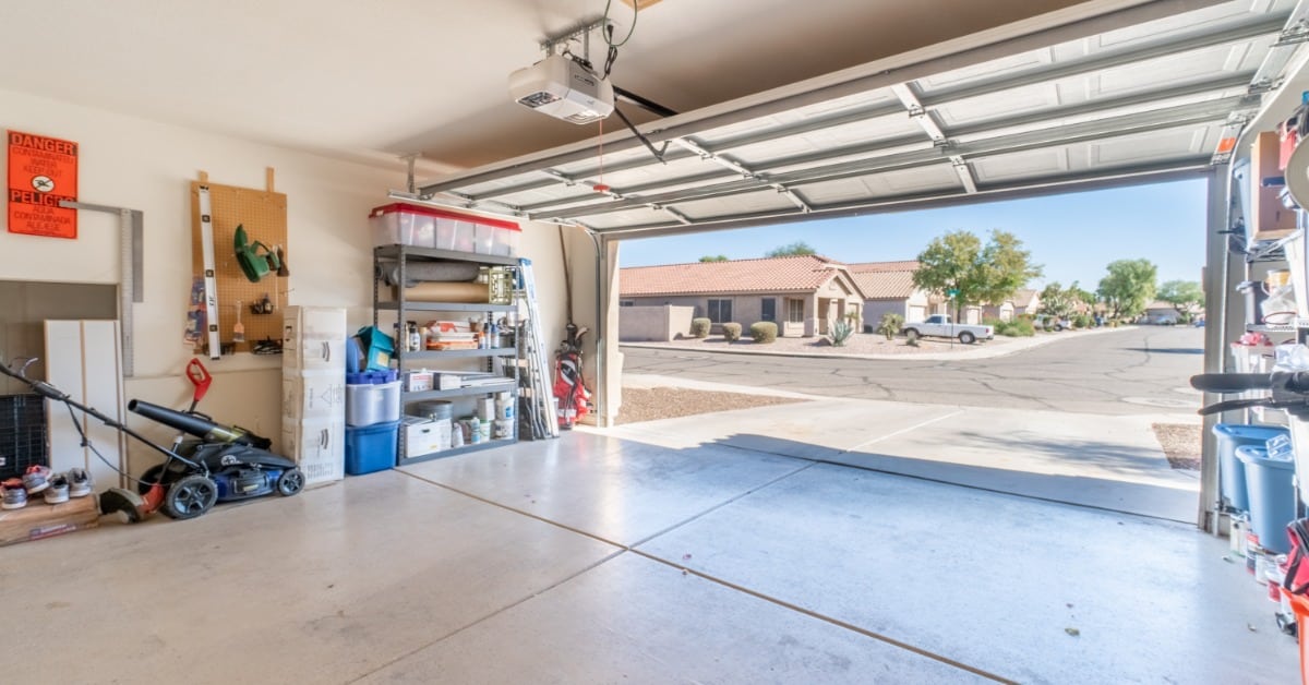 A garage with the door open. There are residential homes across the street with a truck in the driveway.