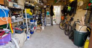 A garage with a lot of clutter in it. The garage has shelves that are flled with ll manner of materials.
