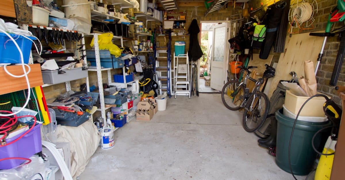 A garage with a lot of clutter in it. The garage has shelves that are flled with ll manner of materials.