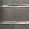 A wall with horizontal slats cutting through them. The panels are dark gray while the slits are steel.
