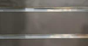 A wall with horizontal slats cutting through them. The panels are dark gray while the slits are steel.
