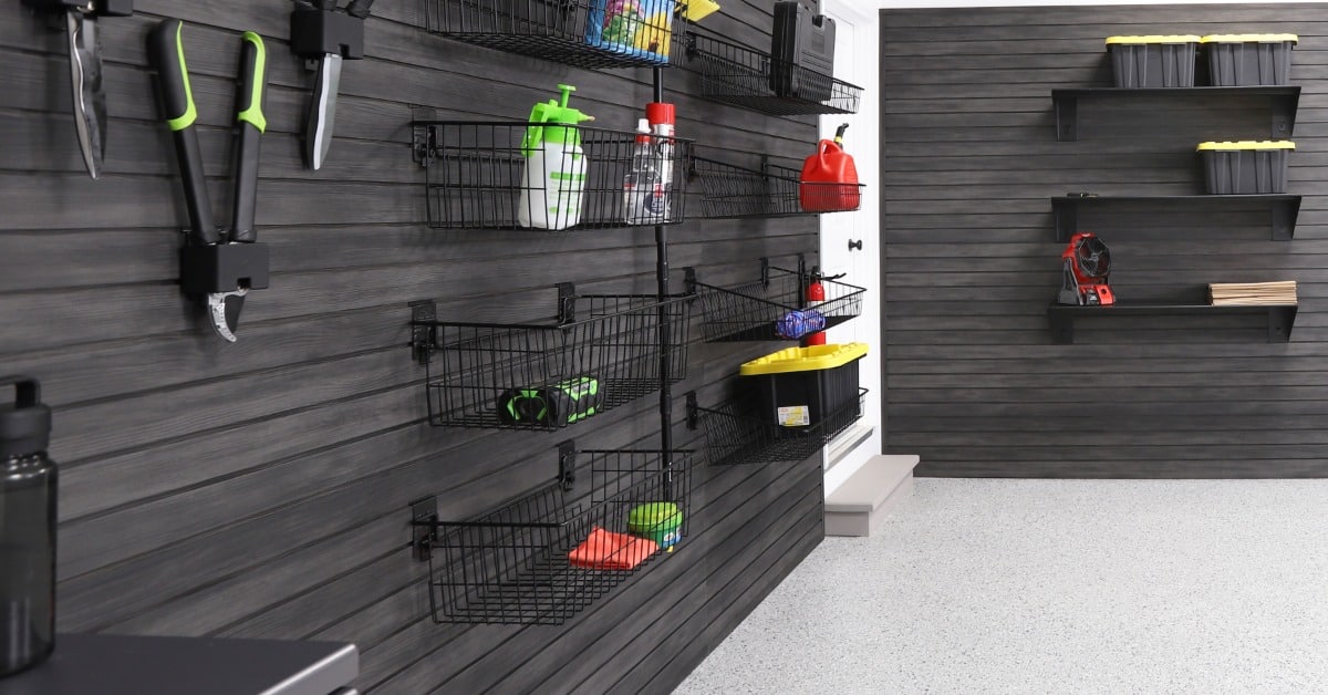 Hedge clippers with green handles are hanging from a wall. The adjacent wall has black tubs on shelves.