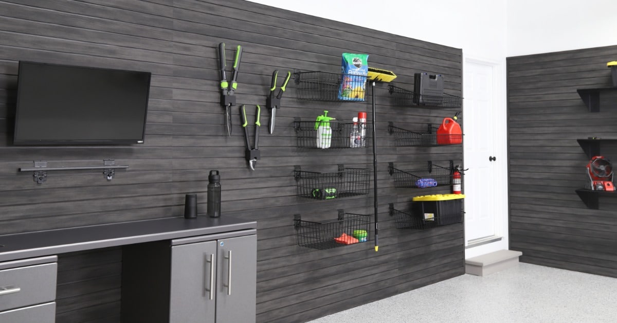 A room with white walls and black wall paneling. The panels are black slatwalls, and they have items hanging.