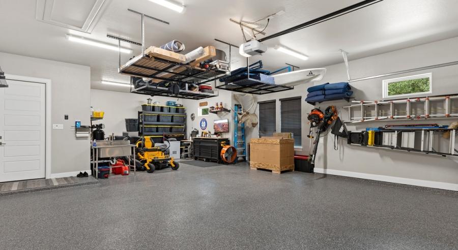 A room with a gray floor and white walls, and many items are stored on the walls. There is also a window to the right of frame.