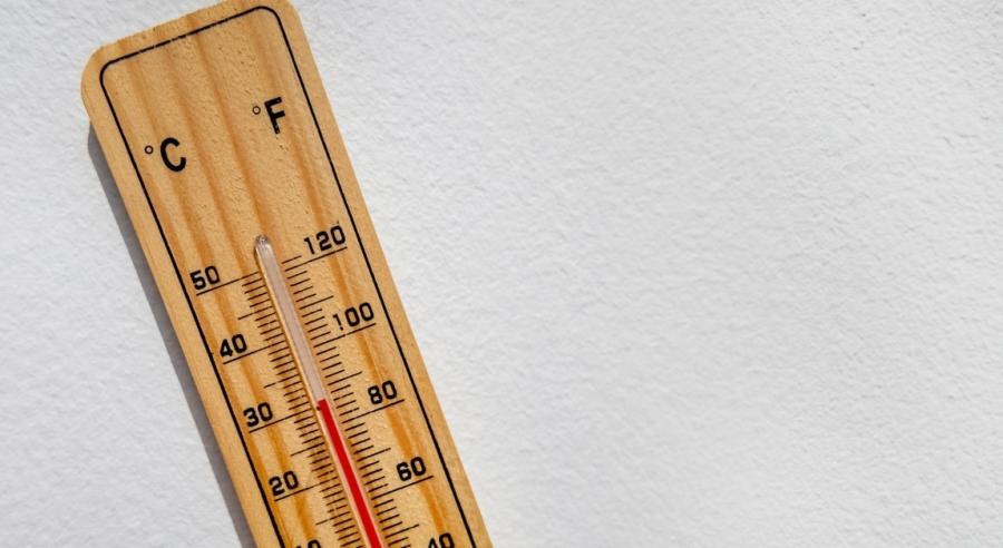 A thermometer is on a white surface. The mercury in the glass tube indicates the temperature is 30 degrees Celsius.